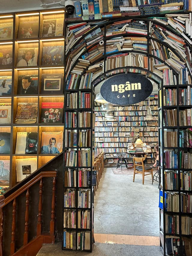 가운데에 타원형 ngâm CAFE 간판이 걸린 검은 책 아치