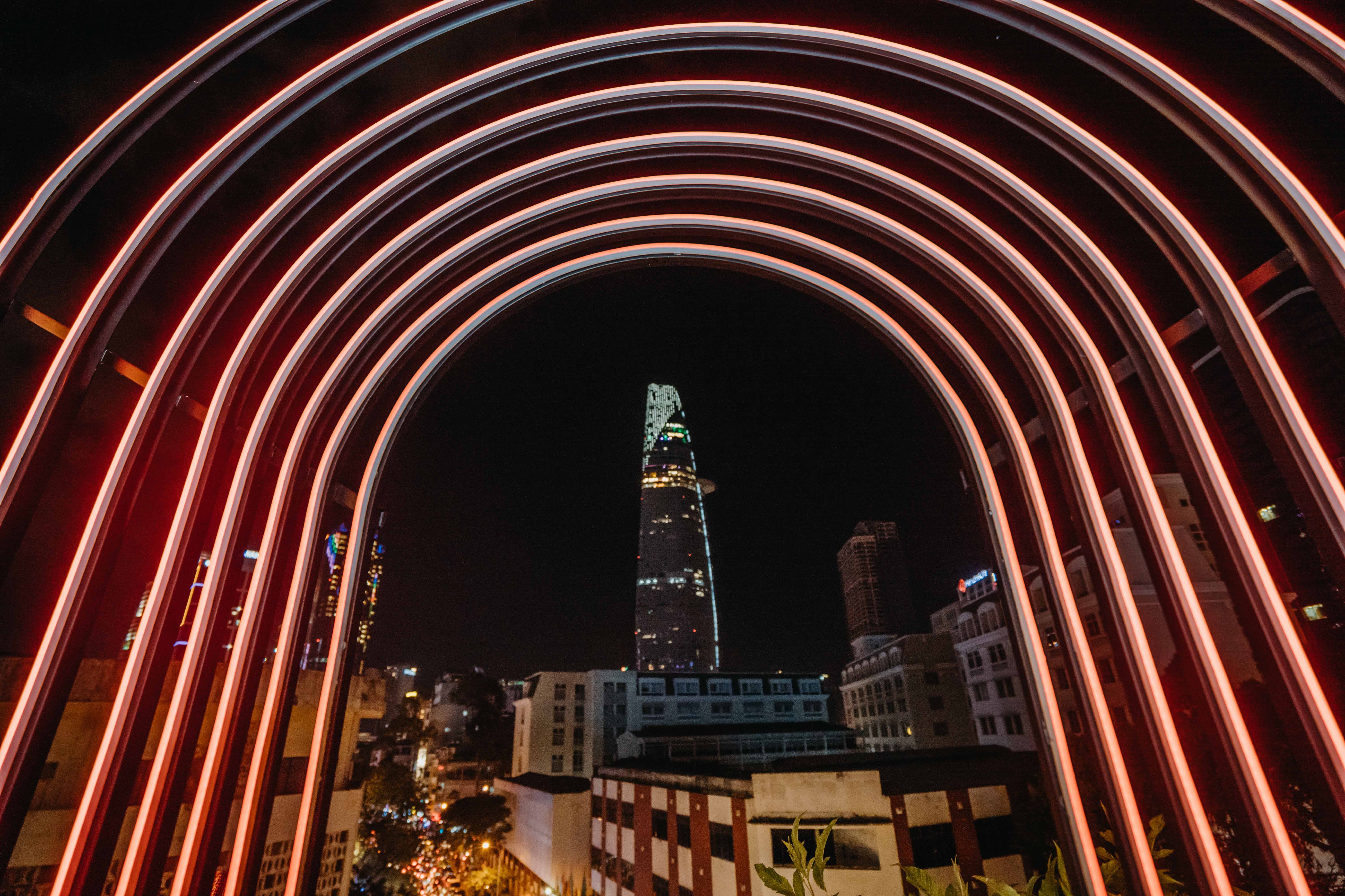 Ba Gac's red neon arches framing the Bitexco tower at night