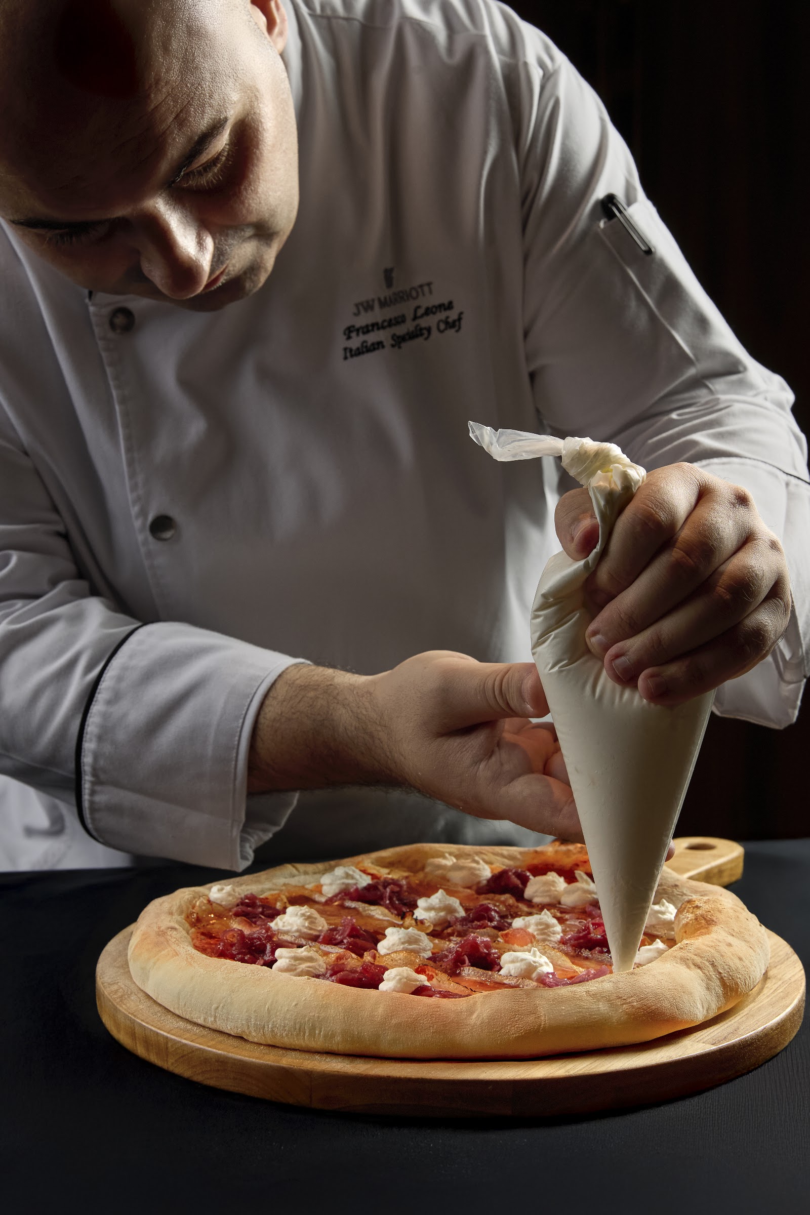 Chef Leone piping pizza