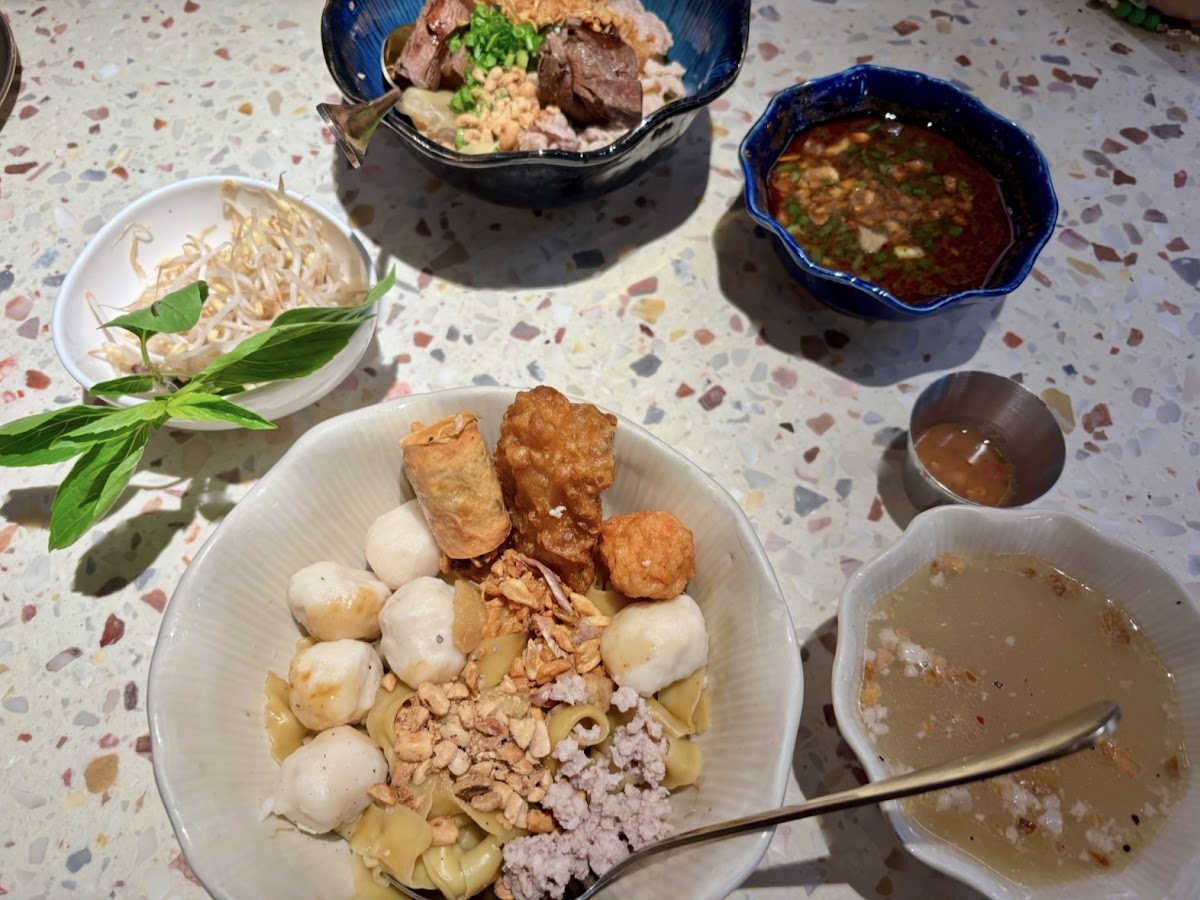 Table spread of boat noodles and sides