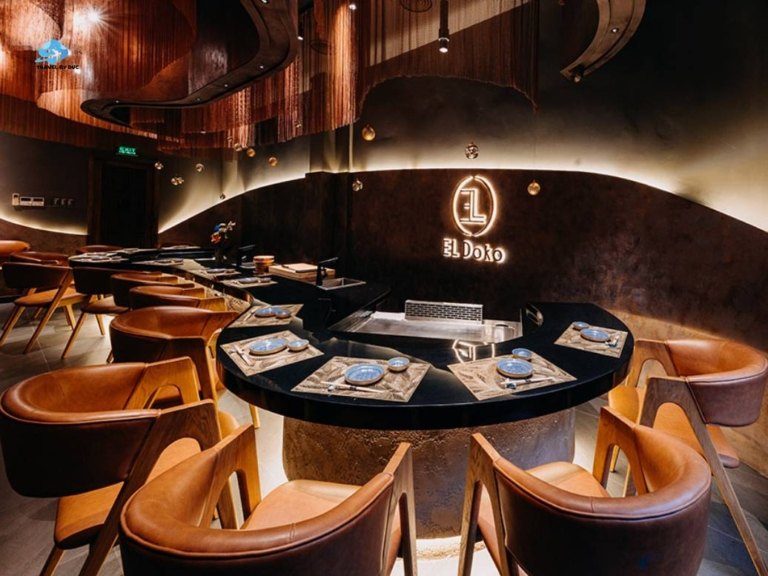 Không gian quầy teppanyaki tối với ghế da và logo EL Doko phát sáng
