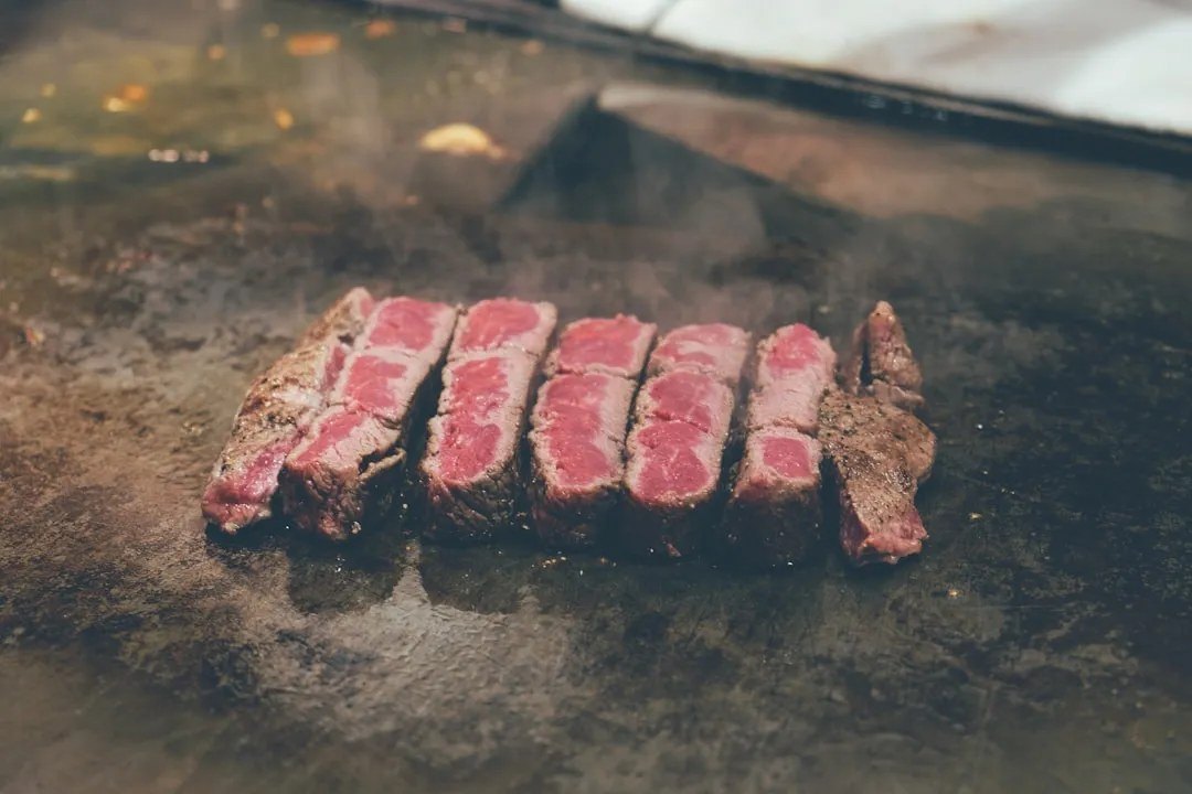 Lát bò wagyu áp chảo nghỉ trên bàn thép, khói bốc lên
