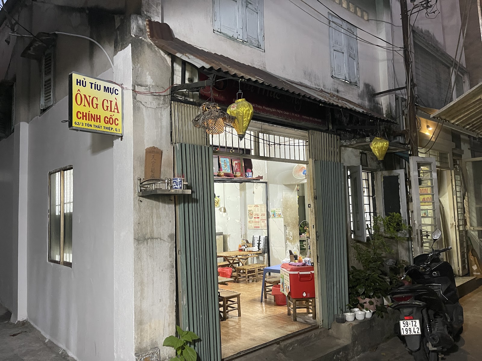 Cửa quán sáng đèn buổi tối — đèn lồng vàng và bảng hiệu trong hẻm