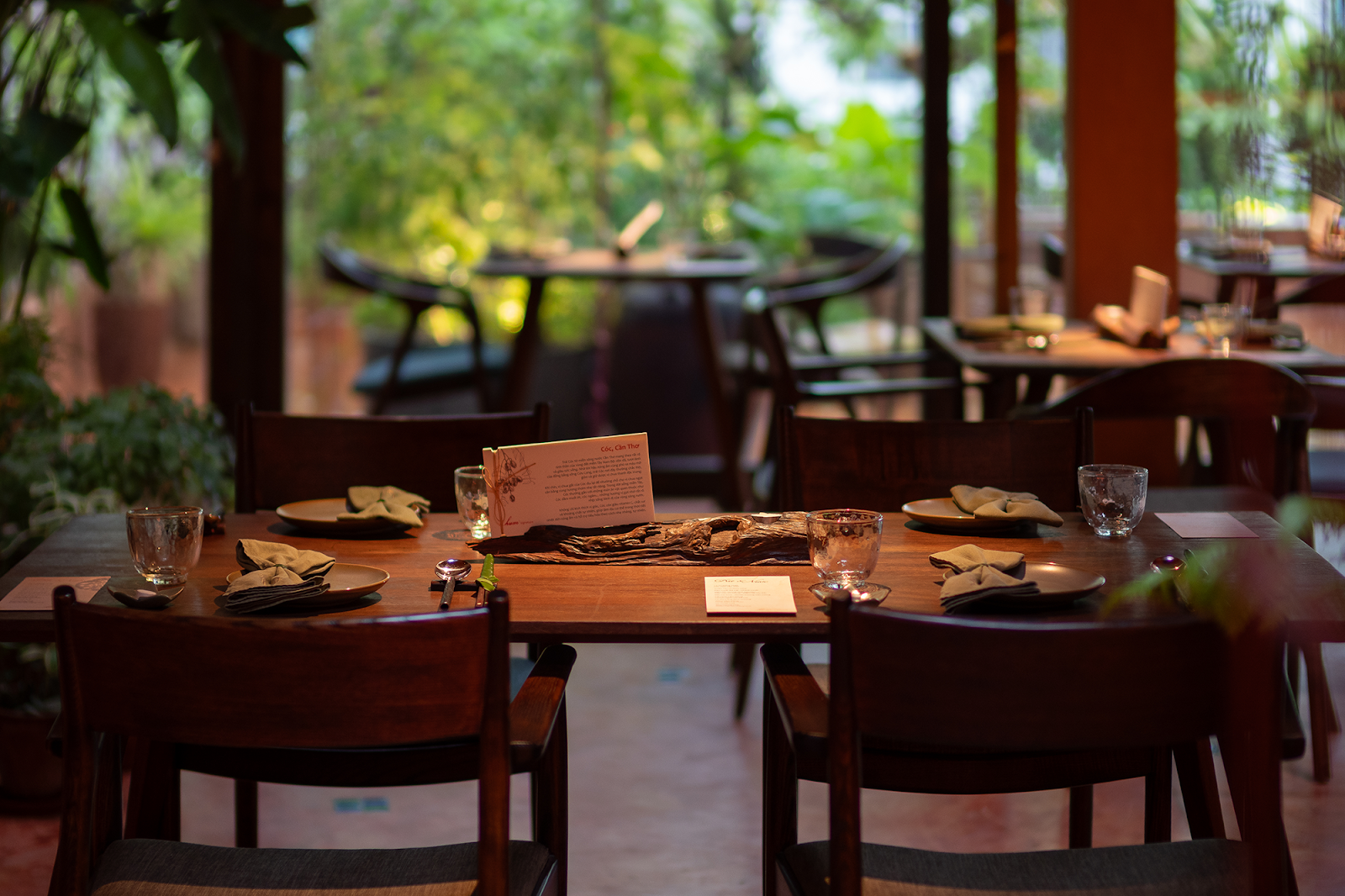Hum Signature's dining room — set wooden tables, glass walls facing the green garden