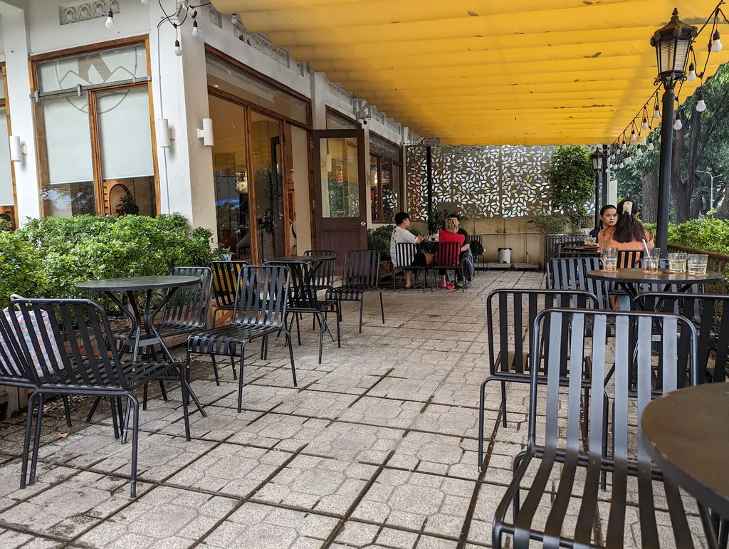 The terrace under the yellow awning, tables looking out to the street