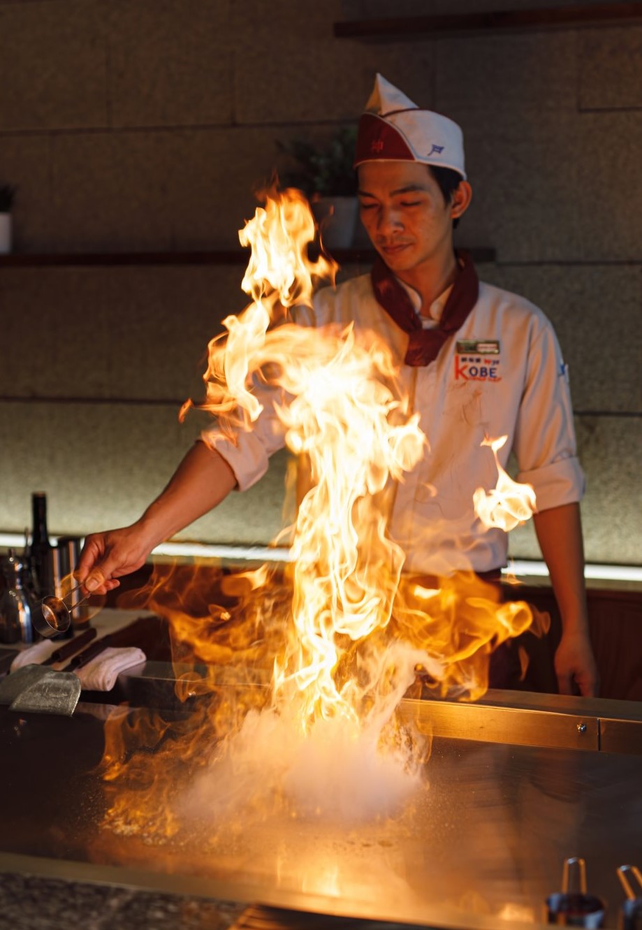 The flambé — fire rising off the teppan in the chef's hands