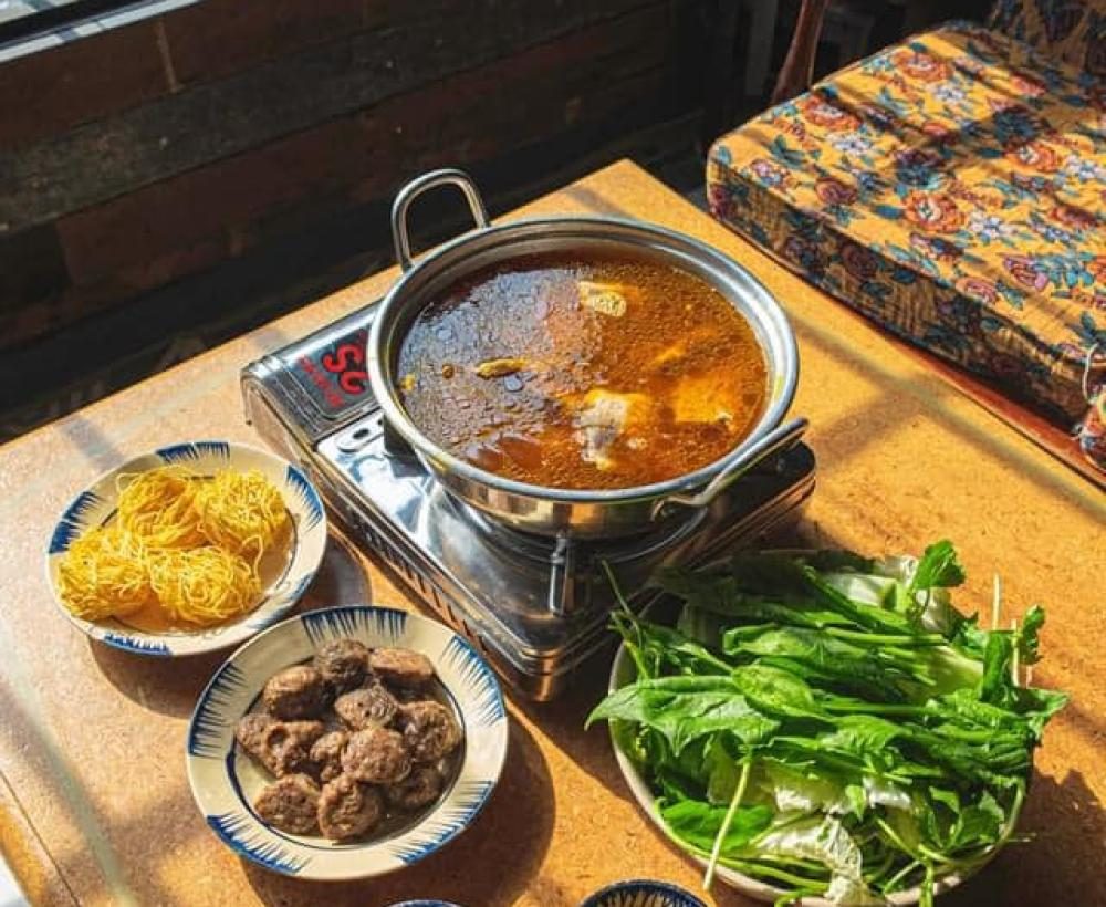 Bàn ăn tại Lẩu Bò Nhà Gỗ — bò viên, mì và rau