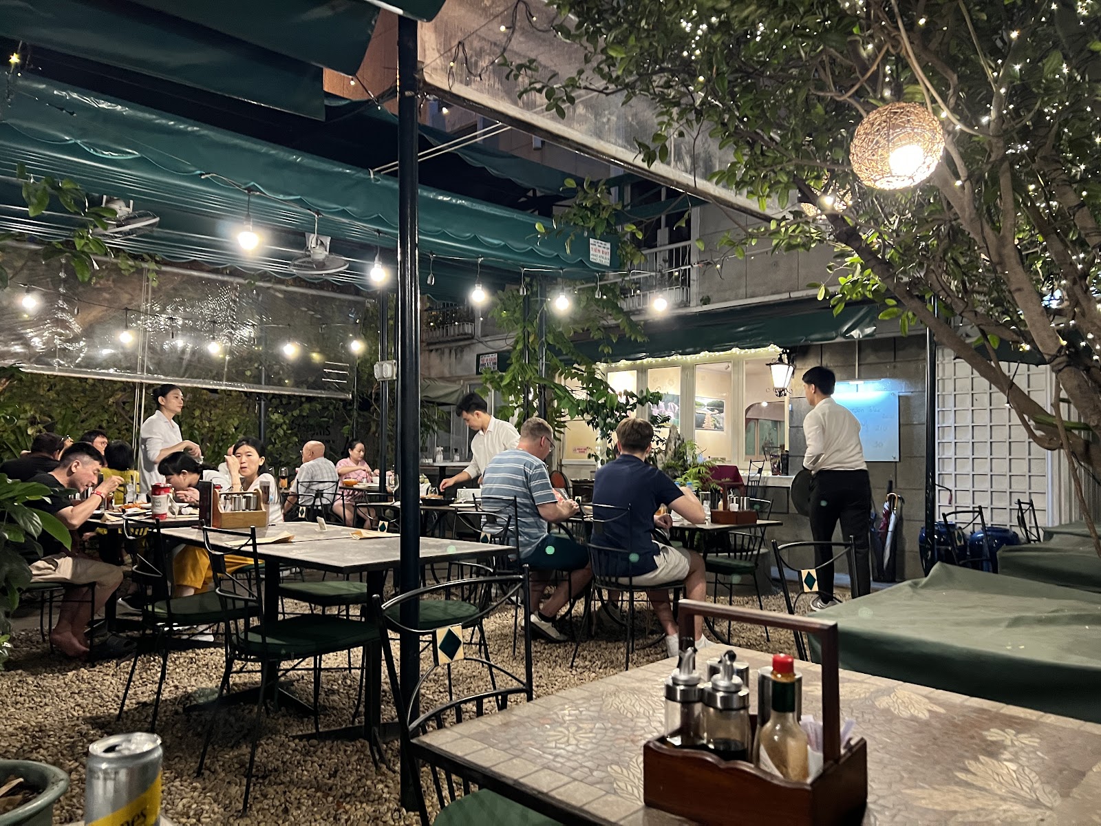 The garden terrace at Le Jardin: leafy tables under the trees inside IDECAF