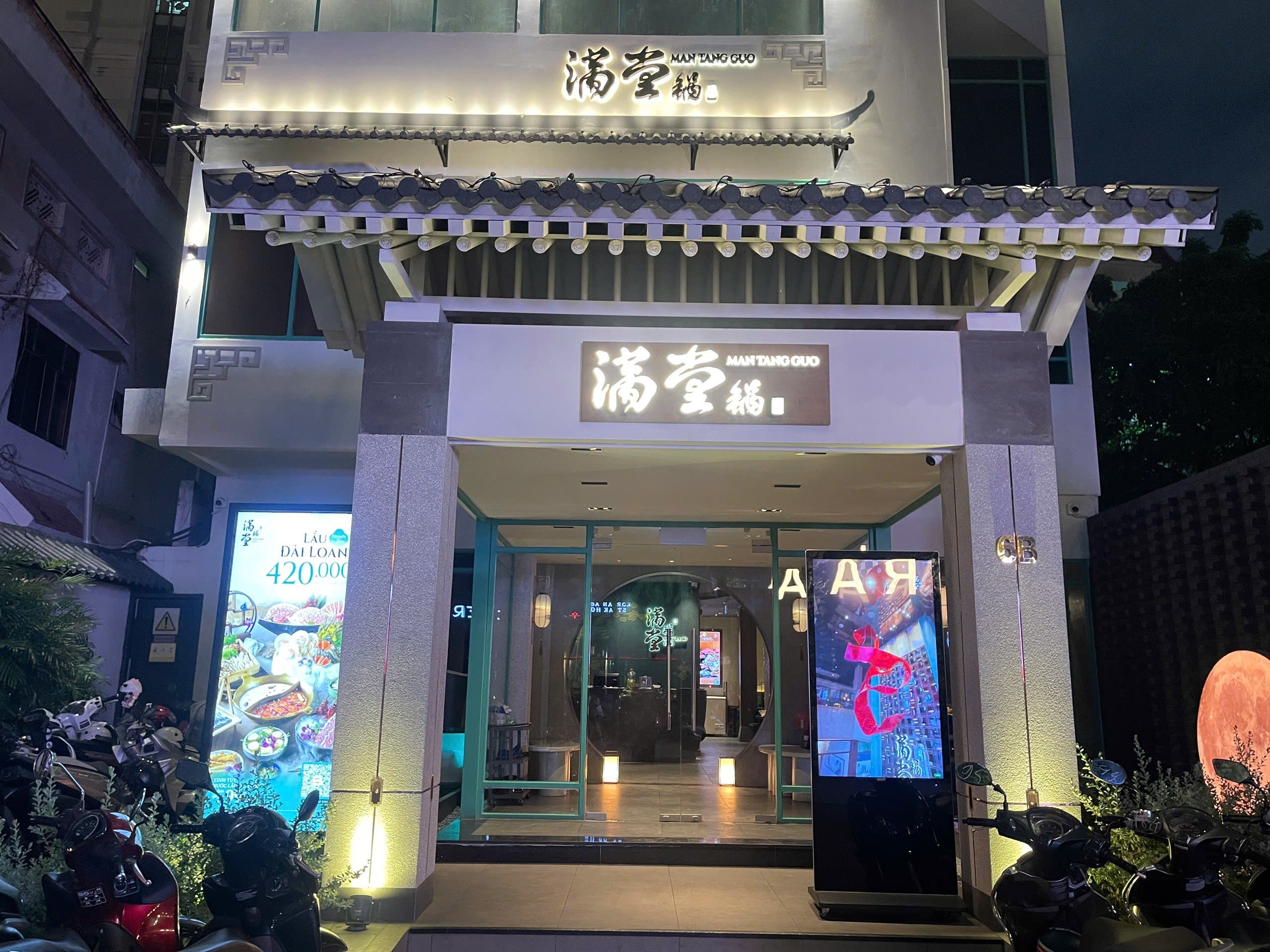Man Tang Guo facade at night — tiled roofs, the glowing 滿堂鍋 sign