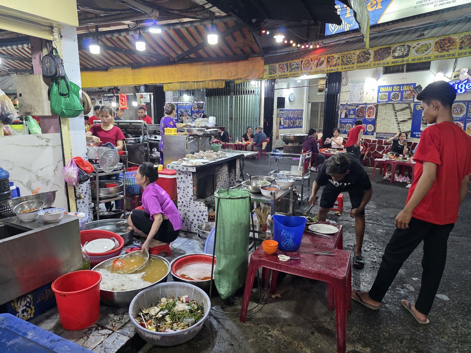 Quán lúc nửa đêm — bếp nóng, bàn nhựa, khách đông.