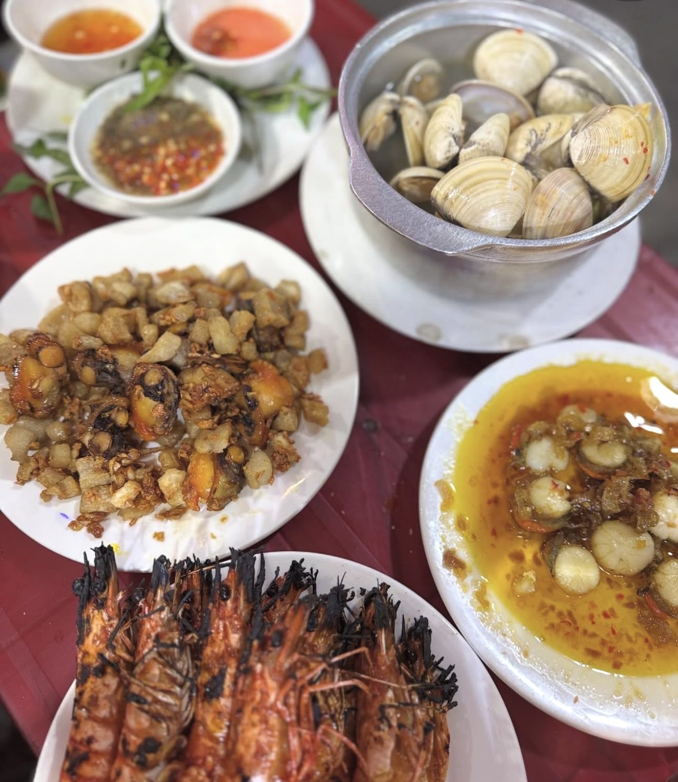 A table full of shellfish — steamed clams, grilled prawns, butter-sautéed scallops.