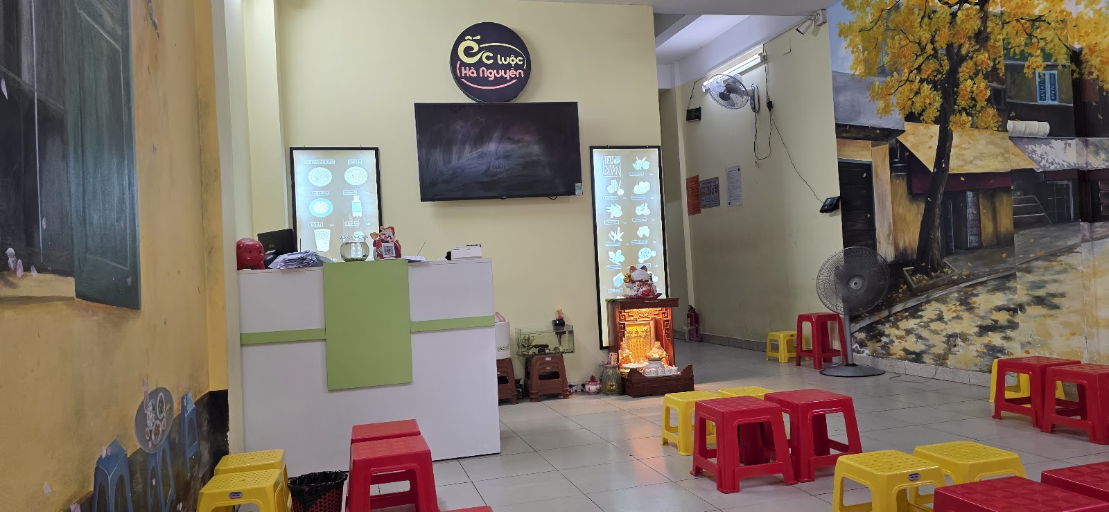 The dining hall at Oc Luoc Ha Nguyen — murals, low stools, the counter