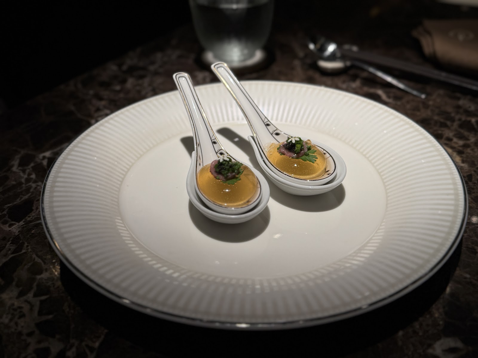Two porcelain spoons of clear consommé
