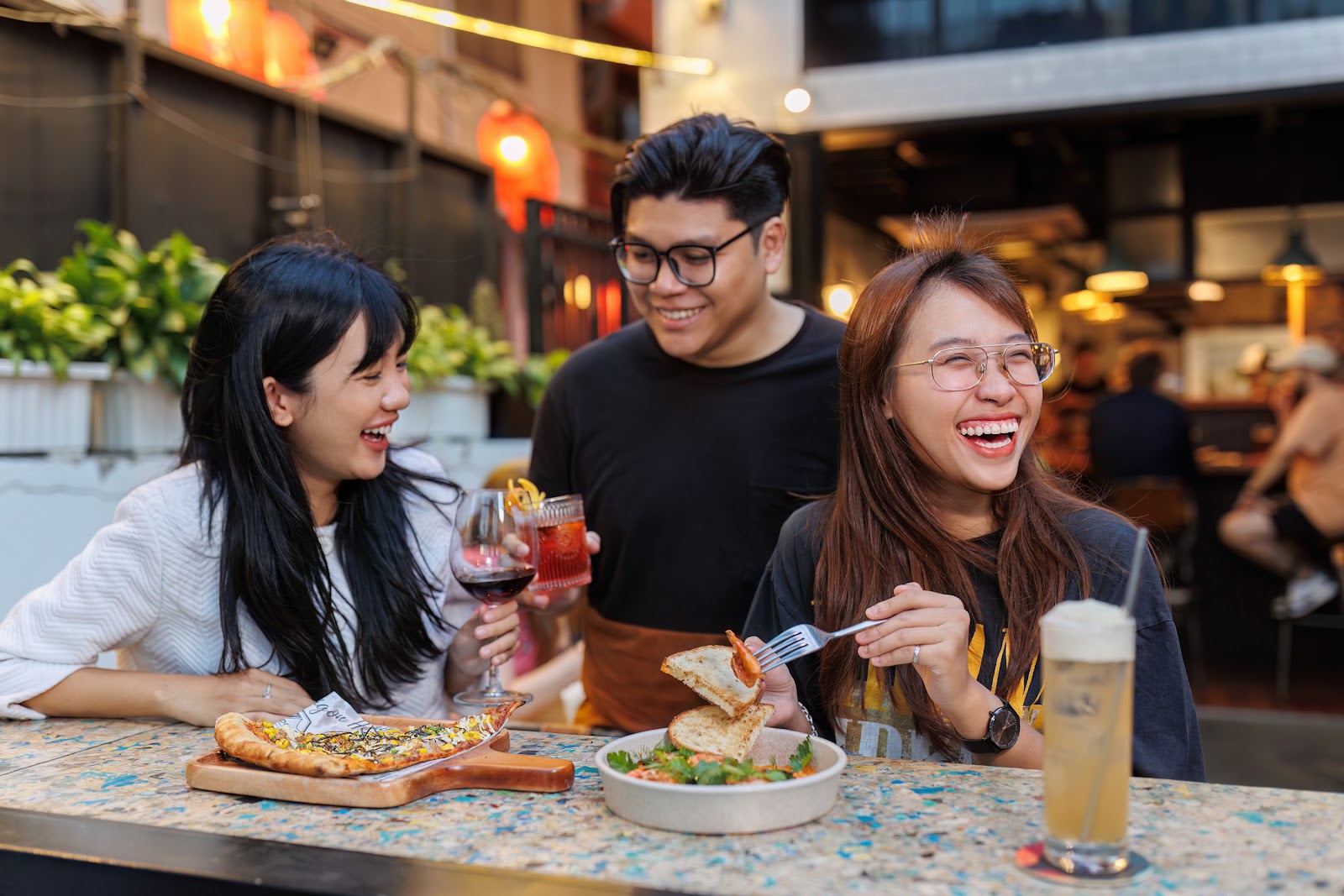 Friends sharing pizza and beer at an outdoor table