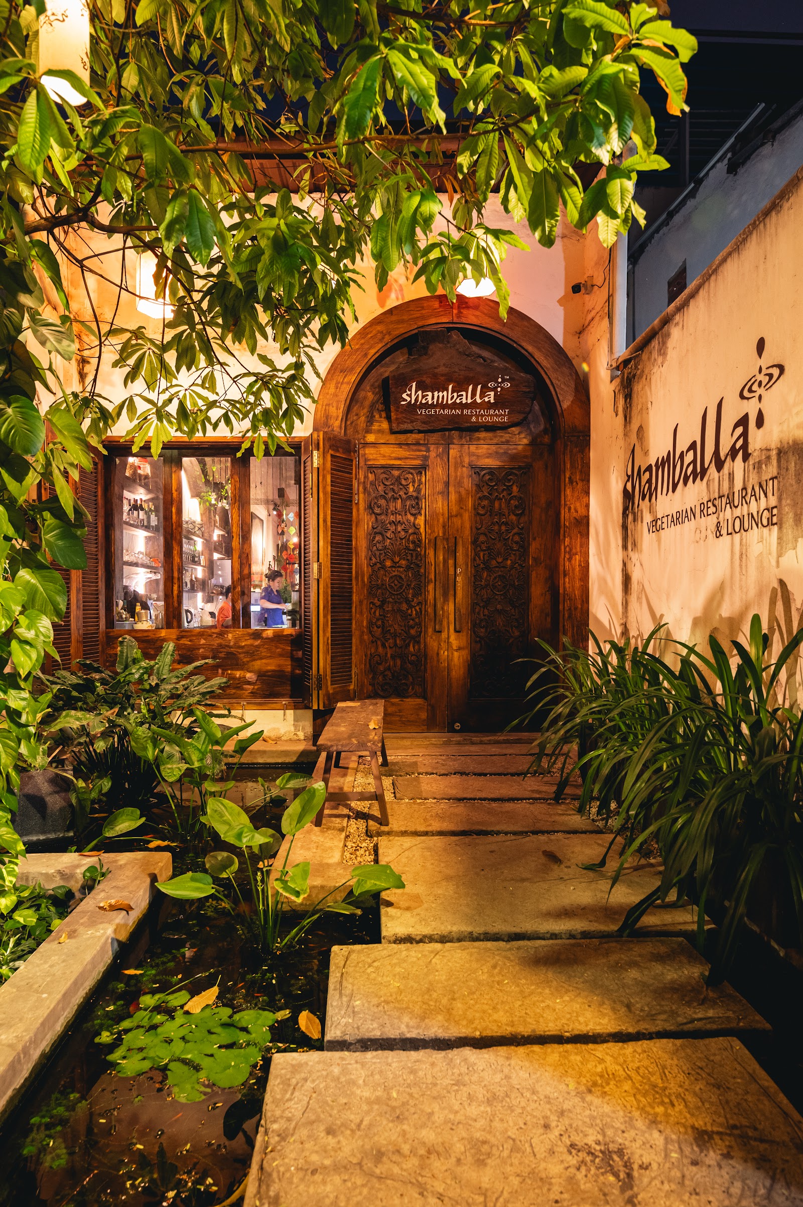 The night garden path at Shamballa — a winding stone walkway in lamplight