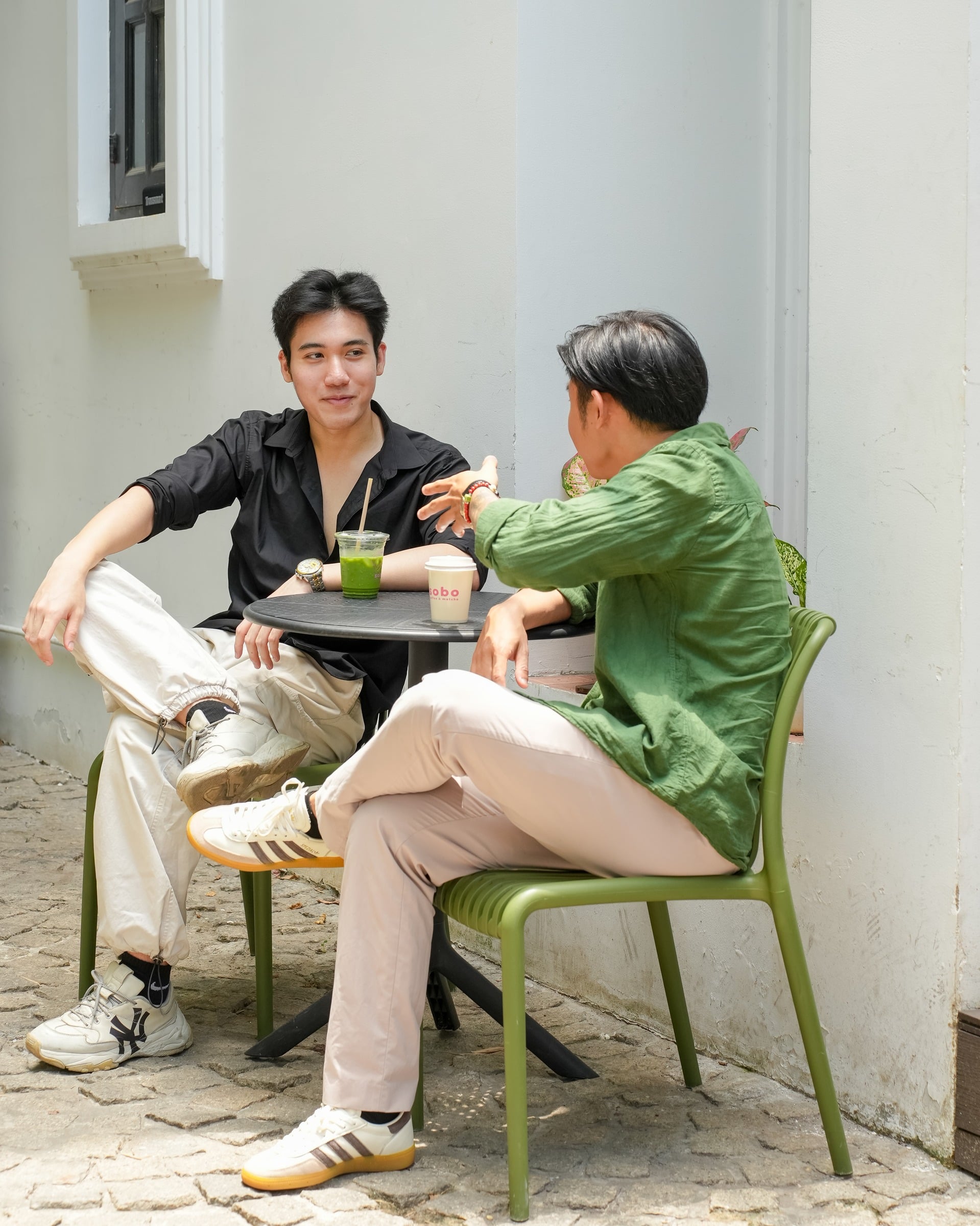 Khách ngồi sân lát đá với ghế xanh xám