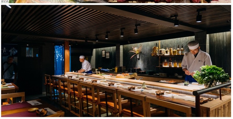 Quầy gỗ dài tại Sushi Aoyama với các đầu bếp đang làm việc