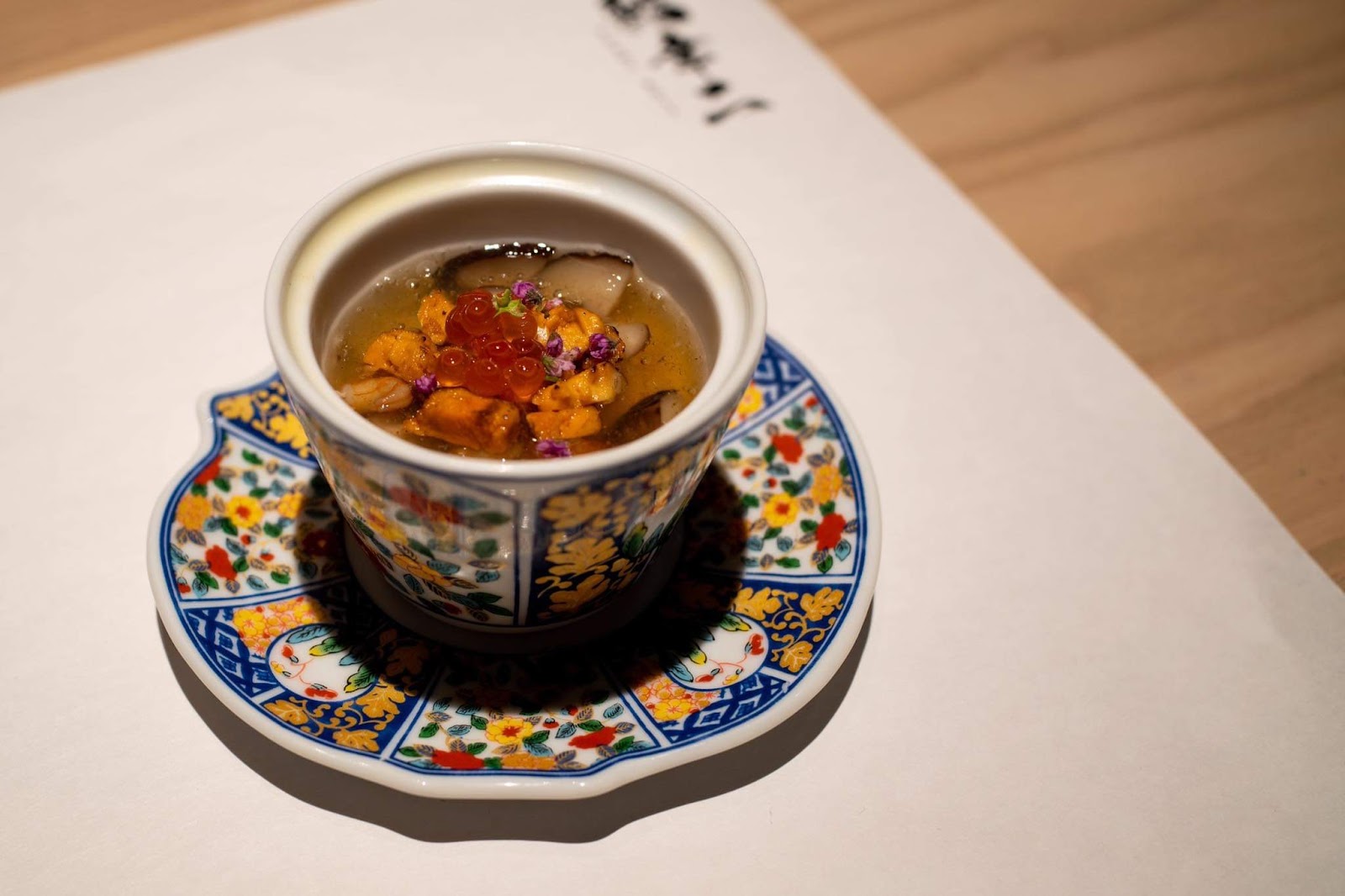 Steamed egg custard cup with uni and ikura on a patterned porcelain saucer