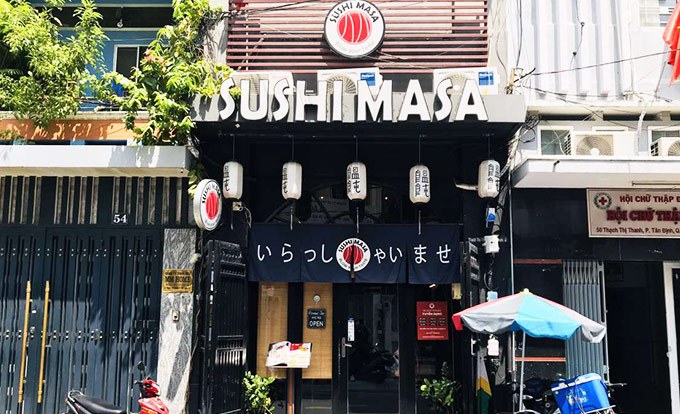 The Sushi Masa storefront with the red vermillion signage and noren curtain