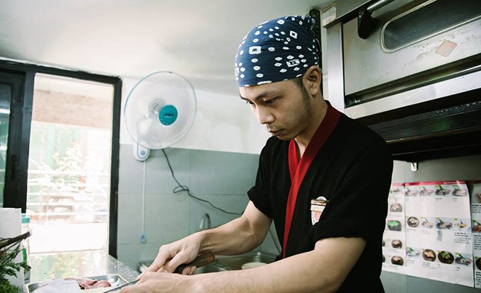 A Sushi Masa chef slicing fish at the counter