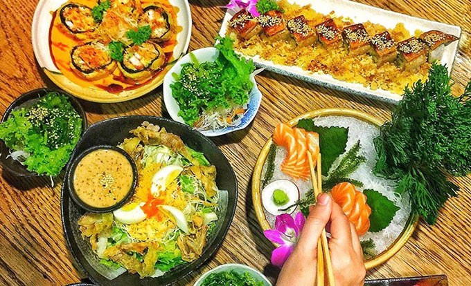 Cả bàn đầy món: cuốn lươn, cá hồi, salad và sushi