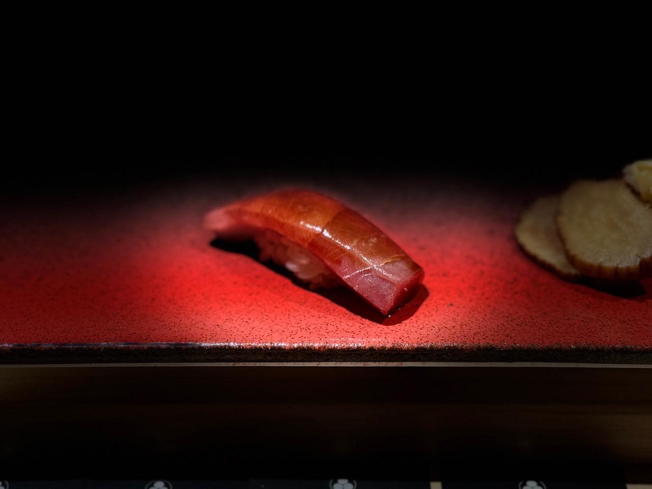 Akami nigiri on red lacquer in the dark
