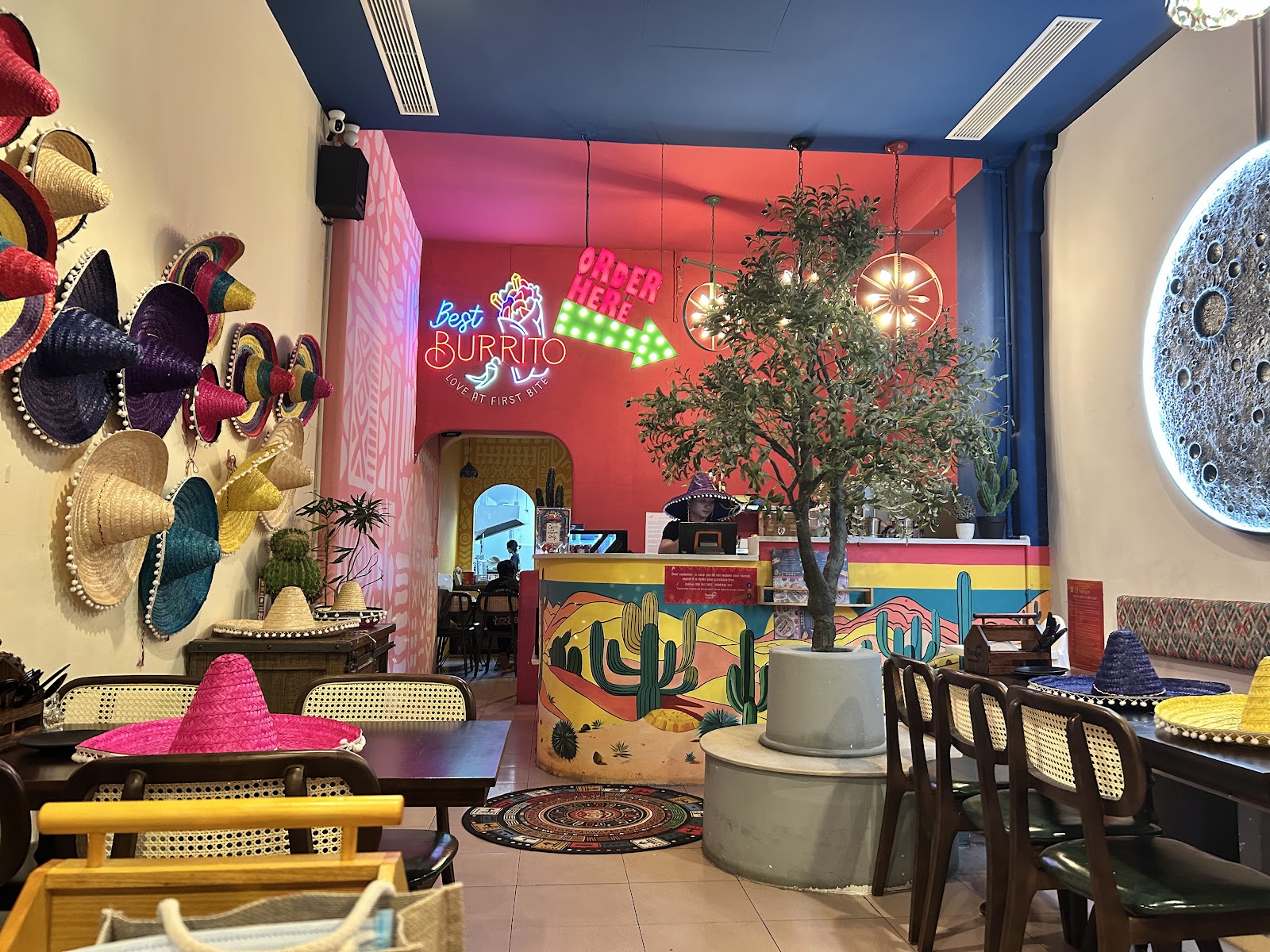 Bên trong TacoLeo hướng về quầy — biển neon "Best BURRITO"