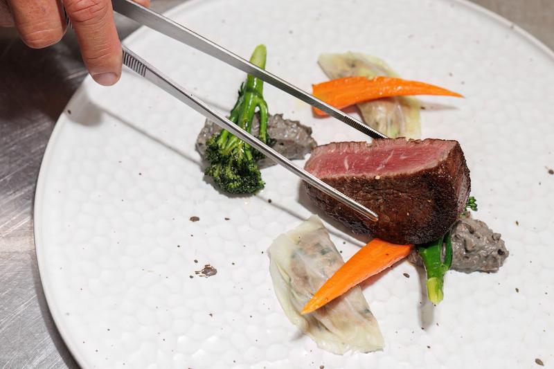 Chef plating beef with tweezers