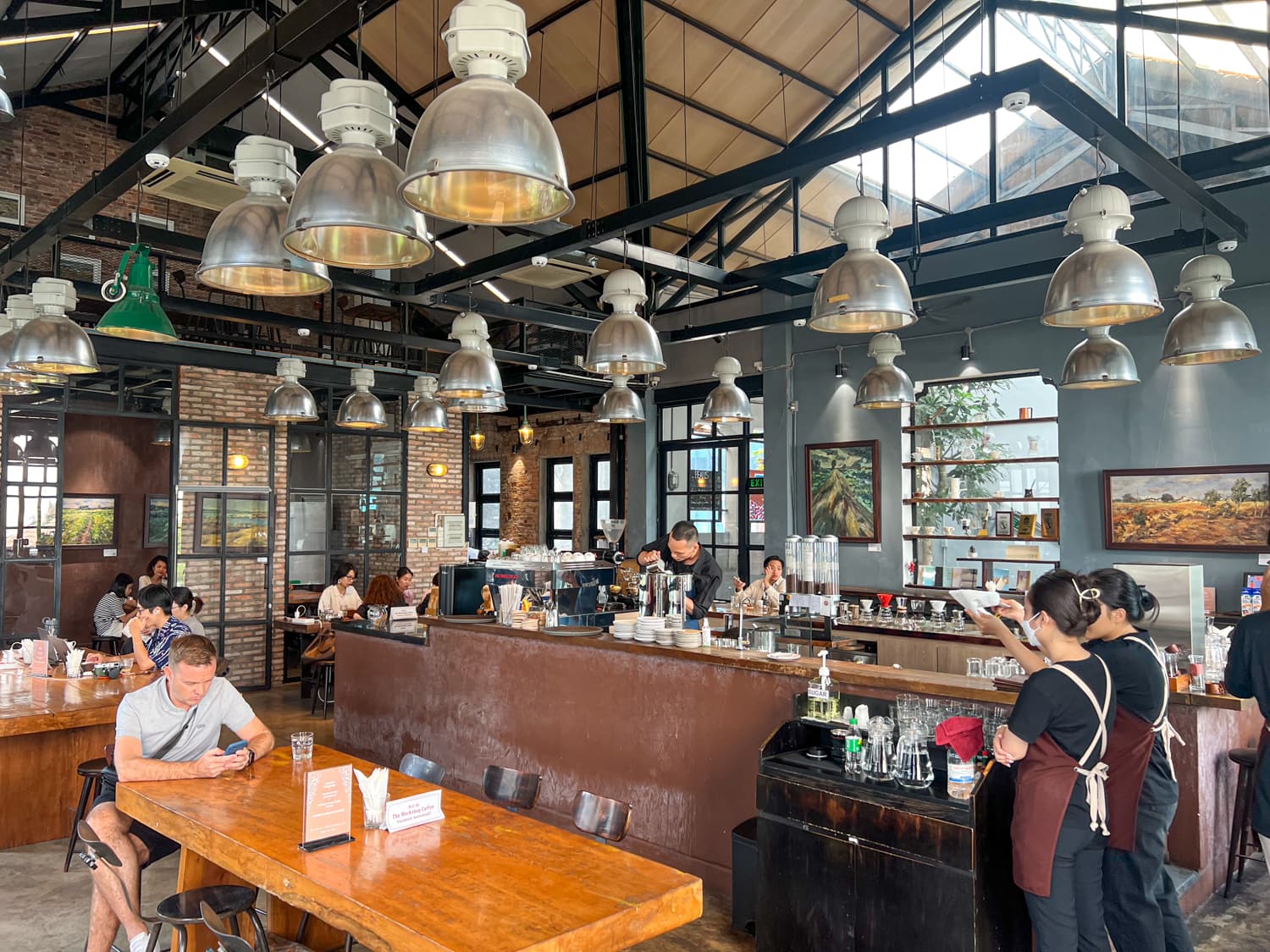 The Workshop main hall — steel trusses, dome pendants, communal tables
