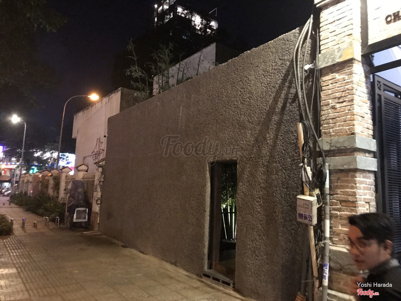 The night facade: an unmarked stone wall, one small door on Dien Bien Phu street
