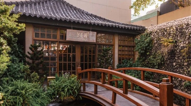 Mặt tiền Yen Sushi Premium — cầu gỗ qua ao dẫn vào quán trà Nhật